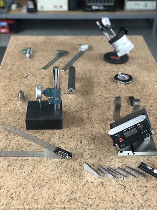 Physical dimensional measurement tools sit atop a granite surface plate in calibration lab