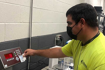 Michelli Weighing & Measurement technician applies a certified scale sticker after scale inspection