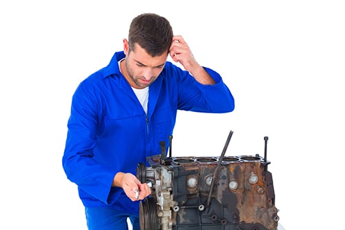 Confused mechanic repairing car engine over white background