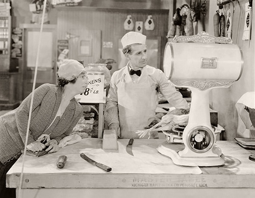 Butcher and customer looking at old scale using obsolete scale to get weight