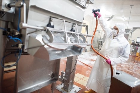 Employee washes down weighing equipment