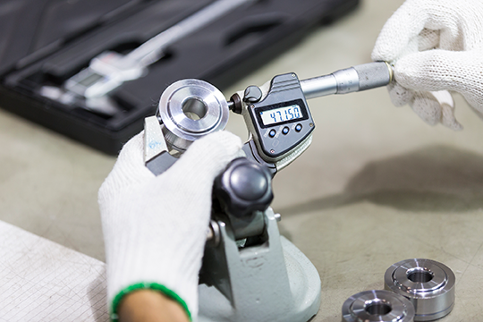 Micrometer being used to measure auto component