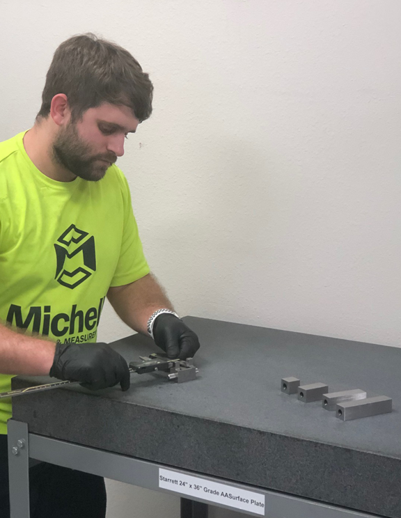 Michelli technician uses steel gage blocks to calibrate a caliper