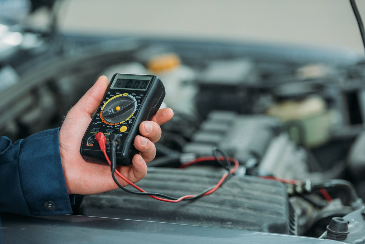 Auto mechanic uses digital multimeter to test automonile power output