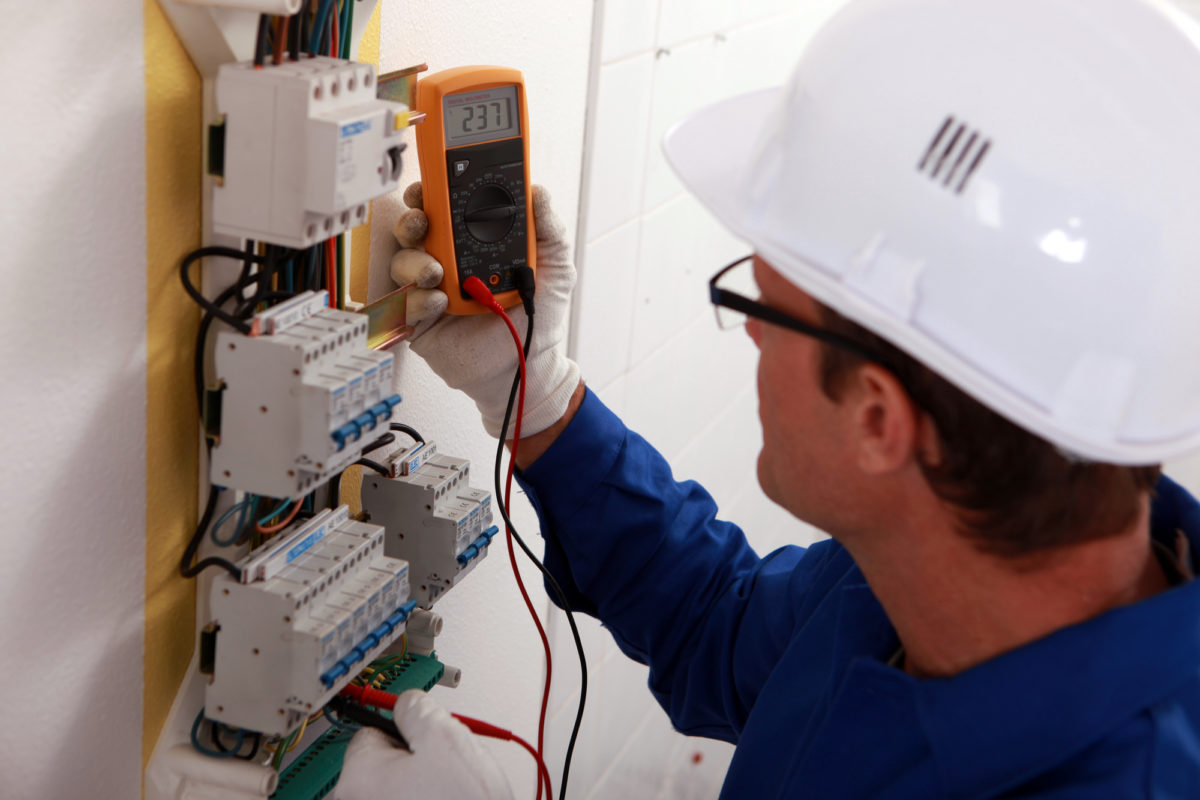 Electrical inspector uses a digital multimeter to read power output