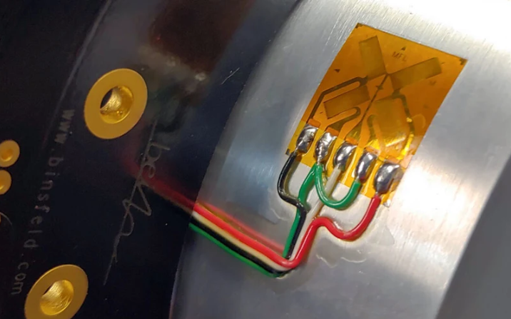 Close-up of a strain gauge sensor bonded to a metal surface for force and load measurement